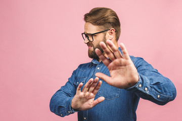 Portrait of a casual man showing stop sign over pink background.