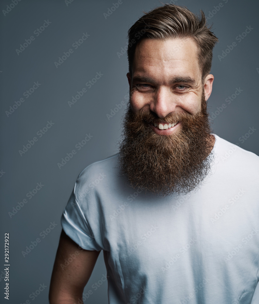 Bearded young man laughing against a gray background - obrazy, fototapety, plakaty 