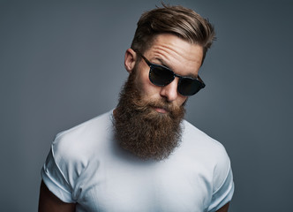 Stylish young hipster with a long beard wearing sunglasses