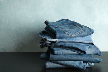 Wall Mural - Stack of jeans pants on black table, space for text