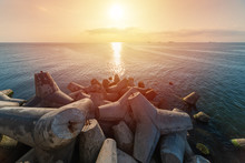 Beautiful Sunset Seascape. Breakwaters Tetrapods Ashore Of Pier. Cargo Ships On The Horizon. Travel Dreams And Motivation