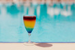 Rainbow coctail on the swimming pool background.. Resort tropical hotel in summer day and fresh water. Copy space, selective focus.