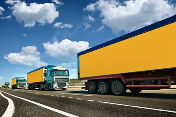 Yellow truck is on highway - business, commercial, cargo transportation concept, clear and blank space on the side view