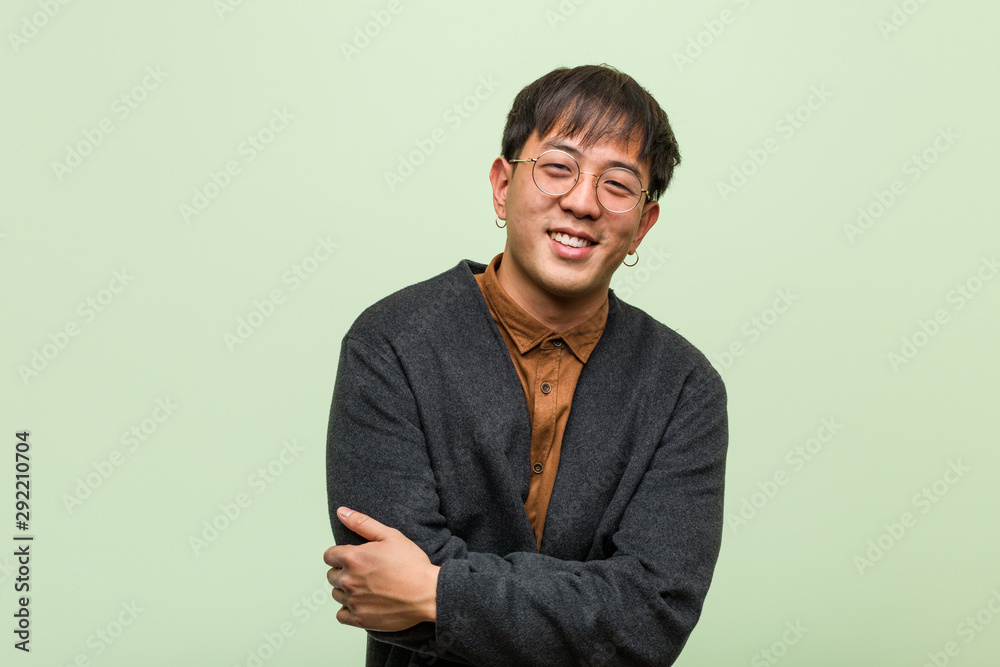 Young chinese man wearing a cool clothes style against a green background - obrazy, fototapety, plakaty 