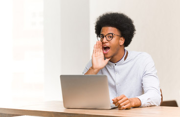 Wall Mural - Young black man using his laptop whispering gossip undertone