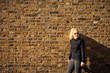 © Cavan Images - Attractive blonde posing against brick wall