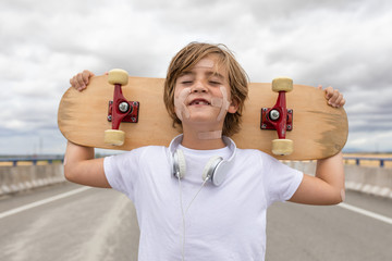 young boy in white T-shirt, music helmets and skateboard