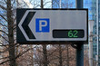 Traffic sign board showing number of parking spaces and arrow pointing to park lot, text can be added to white space, blurred trees and buildings background