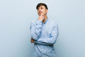 Wall Mural - Young hispanic business man looking sideways with doubtful and skeptical expression.