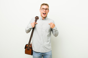 Wall Mural - Young caucasian business man surprised pointing with finger, smiling broadly.