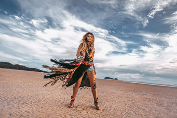 young stylish hippie woman on the beach at sunset portrait