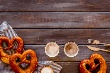 Wall Mural - Octoberfest table background. Pretzels and beer glasses on dark wooden background top view frame copy space