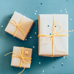 Family holiday celebration. Top view of three beige gift boxes on blur teal blue background.