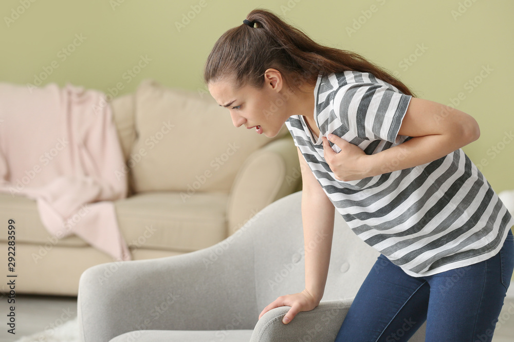 Young woman suffering from heart attack at home
