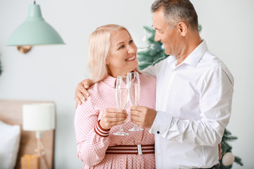 Wall Mural - Mature couple with glasses of champagne celebrating Christmas at home