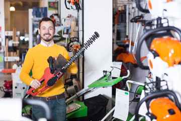 Wall Mural - Guy deciding on best hedge cutter