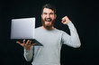 © Vulp - Happt young man celebrating success and holding his new laptop