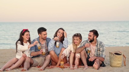 Wall Mural - Group of young friends drinking beer and talking while spending time together at beach near the sea