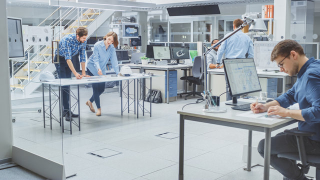 In the Busy Engineering Agency: Diverse Group of Engineers, Technicians, Working on Design for Industrial Engine Prototype. Specialists Talk During Meetings, Work with Drawings, Use Computers