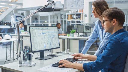 Poster - Engineer Talking With Project Manager and Working on Desktop Computer Using CAD Software with Technical Drawings on the Screen. In the Background Engineering Facility Specialising on Industrial Design