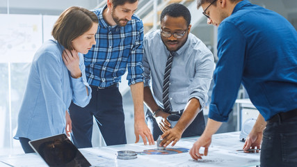 Wall Mural - In the Industrial Engineering Facility: Diverse Group of Engineers, Technicians, and Specialists on a Meeting, Have Discussion, Analyse Engine Design Technical Drafts that are Lying on the Table