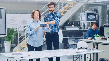 Poster - In the Industrial Engineering Facility: Female Designer with Chief Engineer Uses Smartphone for Augmented Reality App to Manipulate Engine Design Technical Drafts in 3D. High Tech Office. Mock-up