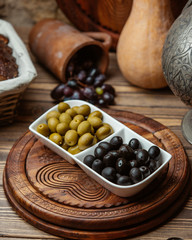 Green and black marianted olive plate on wooden table in rustic style