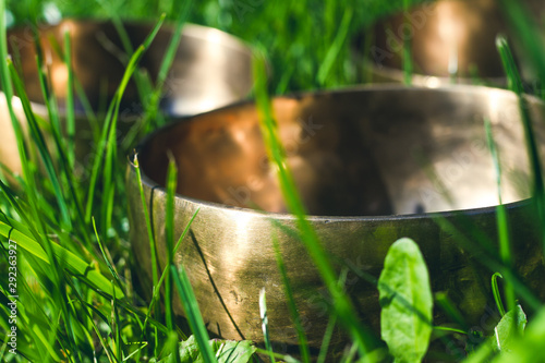 Closeup photo of singing bowls in green grass. Meditation in nature. Balance and energy recovery. Healing Tibetan singing bowls.
