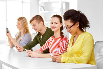 Poster - education, technology and learning concept - group of happy international high school students or classmates with smartphone in classroom