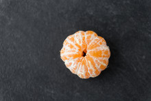 Food, Healthy Eating And Vegetarian Concept - Close Up Of Peeled Mandarin On Slate Table Top