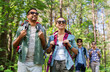 © Syda Productions - travel, tourism, hike and people concept - group of friends walking with backpacks in forest