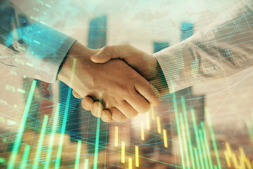 Double exposure of financial chart and world map on cityscape background with two businessmen handshake. Concept of international investment