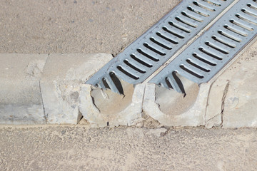 Drainage grating for drain of rain water. two gutters of the drainage system on the sidewalk