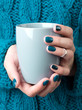 © Darya Lavinskaya - Woman's hands with turquoise manicure hold a grey cup of coffee or tea