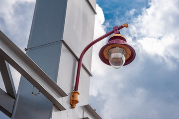 Lantern hanging on a metal pole against a blue sky