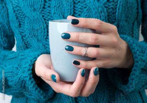 Woman's hands with turquoise manicure hold a grey cup of coffee or tea Lerretsbilde