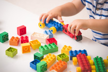 Toddler Child Playing Multi-colored Cubes On The Table. Colorful Plastic Bricks For The Early Development Of The Child. Early Learning And Educational Toys For A Little Boy