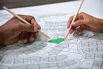 Poster - Hands Holding Pencils Over Cadastre Map
