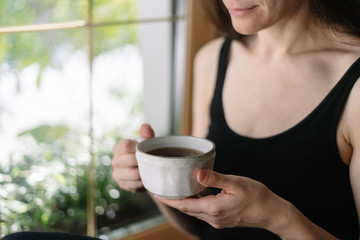 Wall Mural - Young adult woman with cup of beverage in hands