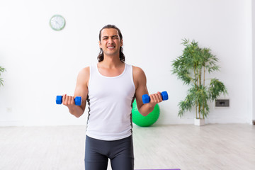 Young handsome man doing sport exercises indoors