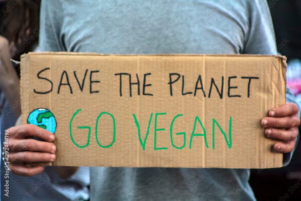 Activist with " Save the planet, Go Vegan" placard at climate change prostest - obrazy, fototapety, plakaty 