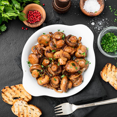 Wall Mural - Fried mushrooms with fresh herbs in white plate. Top view.