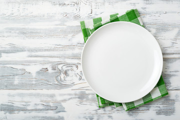 Wall Mural - Empty white  plate and green napkin on white wooden background . Copy space. Top view