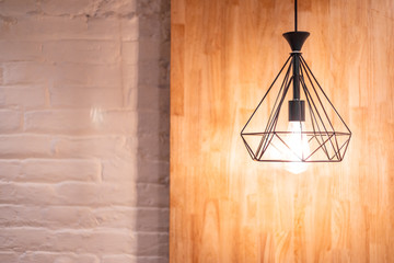 Glowing lght with diamond shaped holder and wooden background hanging by a wire