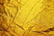 Golden color wrinkled fabric reflector background. Crumpled creasy gold metallic textile material. Closeup. Selective focus