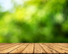 Brown Wood Surface On A Green Background. Green Leaf Background, Blurred Sun, Abstract Bokeh Can Be Used For Displaying Or Editing Your Product.