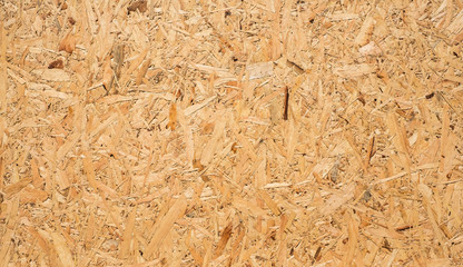 OSB boards are made of brown wood chips sanded into a wooden background. Top view of OSB wood veneer background, tight, seamless surfaces.