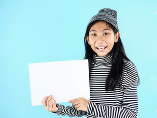 Asian girl in winter costume holding white blank paper on blue background.