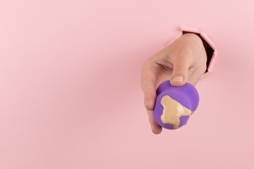 Sticker - Girl hand holds a beauty blender in foundation, concealer from a hole in a pink background. Makeup artist concept, copy space.