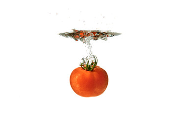 Wall Mural - Fresh Red Tomato Sinking in Water on White Background with splash